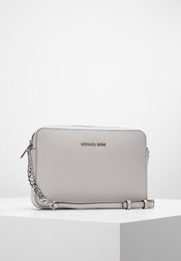 Šedá kožená kabelka přes rameno s hladkou texturou, řetízkem s kovovým povrchem a vyraženým logem značky na přední straně. Obdélníkový tvar.