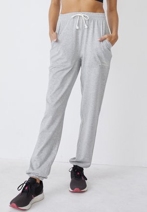 Pantaloni tuta grigi realizzati in tessuto morbido, con vita elastica e coulisse, tasche laterali e design a gamba affusolata.