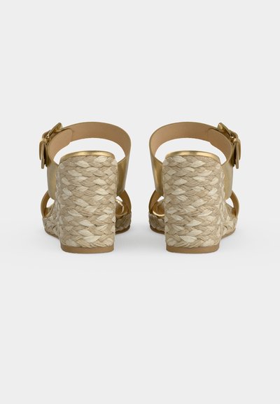 Sandales compensées avec talons en jute tressée, brides de cheville dorées et grandes boucles dorées, vues de dos.