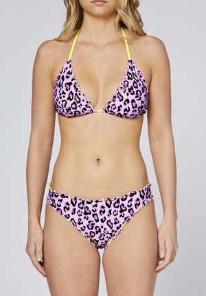 Woman wearing a pink leopard-print bikini with yellow straps, standing against a plain light background, torso visible, arms at sides.