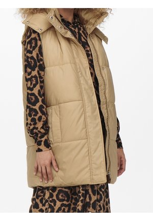 Femme portant un gilet sans manches matelassé beige par-dessus une robe à manches longues imprimée léopard marron et noir, vue des épaules aux cuisses.