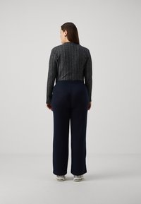 Navy wide-leg pants with a ribbed texture, paired with a fitted, metallic grey long-sleeve top featuring vertical stripes.