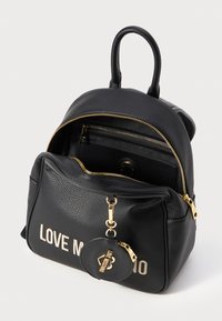 Black leather backpack featuring textured finish, gold zippers, and a front pocket with "LOVE MOSCHINO" printed in white. Includes a circular keychain.
