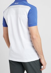 Herrpolo i vitt och blått. Har mjukt tyg, korta ärmar, krage och horisontella ränder på baksidan i grått.