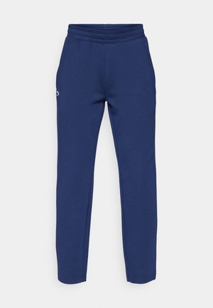 Pantalon de survêtement bleu marine en coton doux, avec une taille élastique et des jambes fuselées. Petit logo brodé près de la hanche.