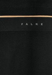 Black leggings made of soft, textured fabric with a fitted design. Features a thin beige elastic band and "FALKE" branding in gray.