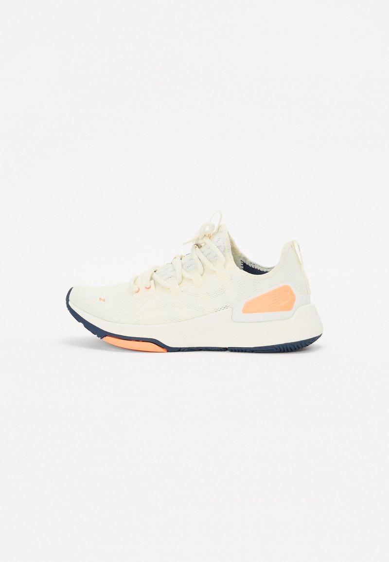 Lightweight athletic shoe in cream color with mesh upper, contrasting navy and coral accents, textured sole, and standard lace closure.