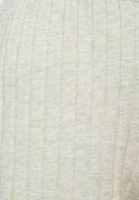 Beige ribgebreide stof met verticale strepen en een zachte textuur. Het ontwerp is eenvoudig en uniform zonder versieringen.