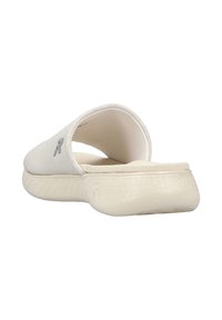 White slip-on sandal featuring a smooth upper, textured sole, and a subtle logo on the side. Open back design for breathability.