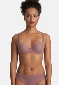 Formad kupa bh i mauve med tunna justerbara remmar. Slät textur och en subtil geometrisk detalj mellan kuporna. Idealisk för vardagsbruk.