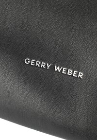 Czarna torba z teksturowanej skóry, z wyraźnym srebrnym logo "GERRY WEBER" z przodu. Gładkie wykończenie z delikatnym wzorem ziarna.