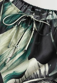 Lengvas juodas marškinys su žalių lapų raštu, elastinga juosmens juosta ir raišteliu. Yra mygtukų paslėpimo ir minkštas tekstūras.