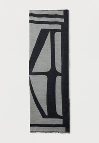 Grå rektangulær skjerf med abstrakte, dristige svarte geometriske former og en tynn frynse langs kantene, lagt flat og brettet vertikalt.