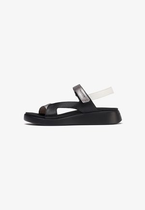 Sandal de cuero negro con un acabado texturizado, que presenta un acento de tira metálica y suela de goma. Diseño de punta abierta y tira de talón ajustable.