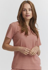 T-shirt rosa a maniche corte con scollo rotondo. Presenta un sottile motivo a nido d'ape e un'etichetta del marchio sull'orlo inferiore.