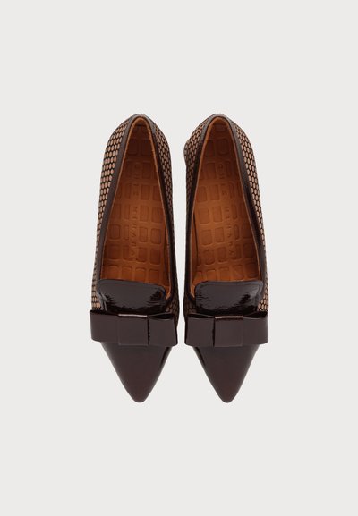 Paire de chaussures marron à bout pointu pour femmes, avec des côtés texturés et un nœud en cuir verni sur chaque bout, vues de dessus sur un fond uni.