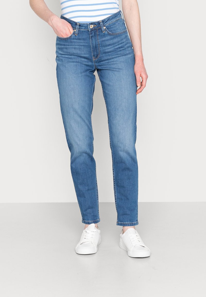 Džíny z lehkého denimu s klasickým rovný fit, vysokým pasem a minimalistickým designem, doplněné bílými teniskami.