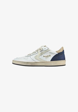 Zapatilla blanca de cuero con acentos grises, talón beige y suela de goma negra. Presenta una superficie texturizada y costuras decorativas. Detalle del logo en dorado.