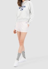 Sudadera gris con el estampado "Michigan", pantalones cortos rosa claro, calcetines grises y zapatillas blancas. Ropa deportiva casual con colores contrastantes.