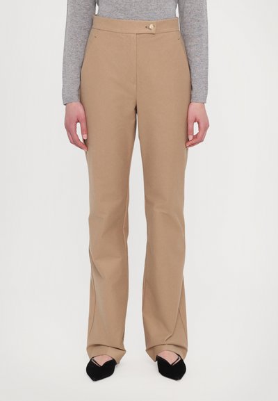 Pantalons beiges avec une taille ajustée, des jambes évasées et une fermeture à bouton. Le tissu semble lisse avec une texture nette.