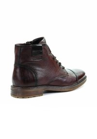 Brązowe skórzane botki za kostkę o gładkiej fakturze, okrągłym nosku, sznurowanym przodzie oraz przeszyciach. Posiadają zamek błyskawiczny oraz drewnianą podeszwę.