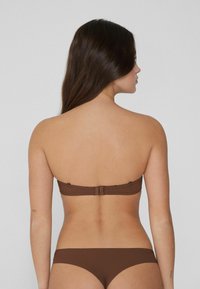 Braunes Bikini-Set mit einem trägerlosen Oberteil und niedrig sitzenden Unterteilen. Glatte Textur mit minimalen Nähten. Verstellbarer Verschluss im Rücken.