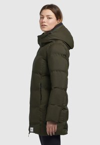 Langer, puffy Mantel in Dunkelgrün, aus glattem Material, mit Kapuze, Reißverschlüssen an den Seiten und einer leicht taillierten Silhouette.