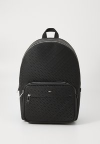 Sac à dos synthétique noir avec un motif texturé, forme arrondie, poche zippée à l'avant et une poignée en sangle en haut. Accents en métal argenté.
