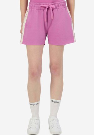Pantaloni corti in cotone rosa con vita elastica e cordoncino, caratterizzati da pannelli laterali con un motivo a logo. Abbinati a calze bianche e scarpe.