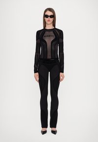 Black long-sleeve mesh top with ribbed detailing and logo, paired with fitted black leggings featuring textured paneling. Slim-fit design.