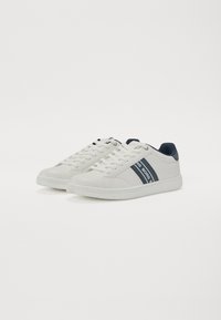 Hvite lær sneakers med marineblå striper og logo detaljer. Flat såle og rund tå. Snøring med teksturerte detaljer.