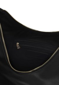 Interiér čiernej kožené tašky so zlatým zipsom. Obsahuje bočnú kapsu so zipsom a hladký, matný povrch.