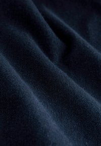 Tume sinine kangas pehme tekstuuriga ja nähtava peene kootud struktuuriga. Materjal näeb välja veidi kortsus, mis suurendab selle kolmemõõtmelisust.
