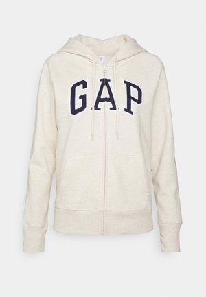 Zippered cream hoodie featuring a kangaroo pocket and embroidered navy "G.A.P." logo on the front. Soft texture, hood with drawstrings.
