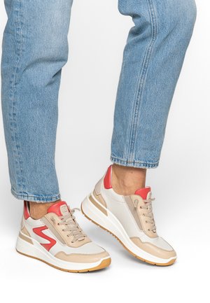 Beige-weiße Sneaker mit roten Akzenten, strukturiertem Leder und synthetischen Materialien, mit Schnürdesign und klobiger Sohle.