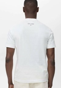 White short-sleeve t-shirt made of cotton, featuring a small printed label on the back with the text "Côte d'Azur 24."