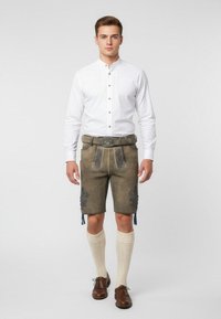 Traditionella lederhosen i brunt mocka med blå broderier, ihop med en vit skjorta, crèmefärgade knästrumpor och bruna läderskor.