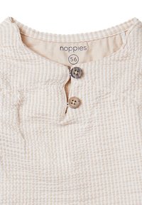 Beige, geripptes Stoffoberteil mit rundem Kragen und Knopfverschluss. Verfügt über zwei dunkle Knöpfe und ein Etikett mit der Größe 56. Weicher Stoff.