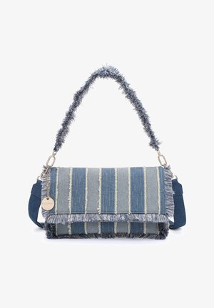 Rechthoekige denim handtas met verticale versleten strepen, franjes aan de randen, een pluizige handgreep en een metalen label dat aan een ketting hangt.