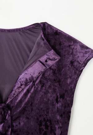 Abito in velluto viola caratterizzato da una texture morbida, maniche corte e un design a v con una leggera lucentezza. Ci sono sottili motivi sul tessuto.
