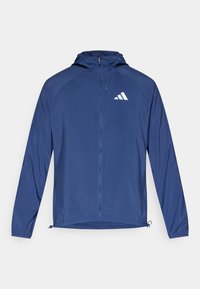 Ελαφρύ μπουφάν σε ναυτικό μπλε χρώμα με κουκούλα και φερμουάρ. Διαθέτει μανίκια ραγκλάν, ελαστικές μανσέτες και λευκό λογότυπο στο αριστερό στήθος.