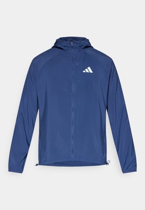 Giacca leggera blu navy con cappuccio e chiusura a zip. Caratterizzata da maniche raglan, polsini elastici e logo bianco sul petto a sinistra.