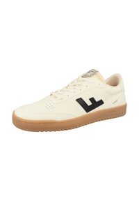 White leather sneaker with black logo, perforated toe box, and beige gum sole. Features flat laces and padded collar. Minimalist design.