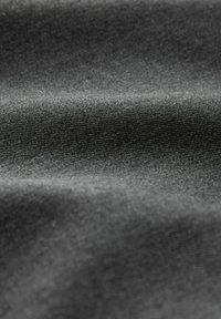 Gros plan sur un tissu gris foncé montrant une texture douce et finement tricotée avec des plis délicats et des ombres subtiles.