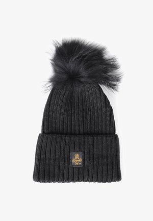 Bonnet en tricot noir avec un revers à côtes replié, surmonté d'un pompon en fausse fourrure noir et d'un petit patch logo sur le revers.