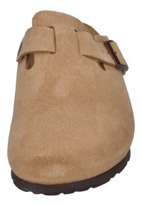 Béžové semišové dreváky s dvoma nastaviteľnými popruhmi s tmavým kovaním, zaoblenou špičkou a textúrovaným povrchom. Gumová podrážka pre grip a pohodlie.