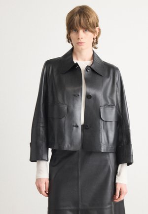 Schwarze Leder-Cropped-Jacke mit breitem Kragen, vorderem Knopfverschluss und zwei aufgesetzten Taschen auf der Brust. Glatte, geschmeidige Textur.