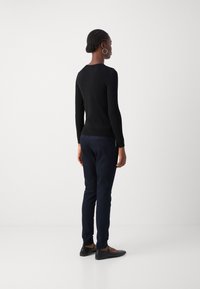 Černý dlouhý rukáv, přiléhavý střih s kulatým výstřihem, v kombinaci s námořnickými slim-fit kalhotami a černými plochými botami. Jednoduchý, elegantní vzhled.