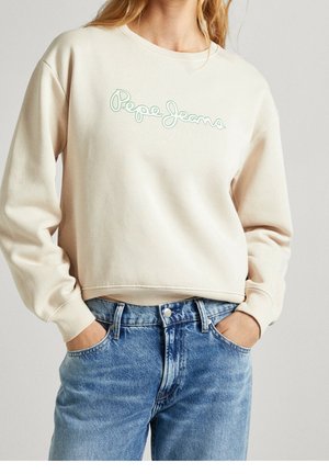 Sweatshirt beige court avec logo "Pepe Jeans" vert clair. Présente un col rond et des poignets côtelés. Associé à un jean en denim bleu clair.