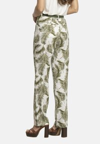 Pantalones blancos de corte holgado con un patrón de hojas de palmera verdes, que cuentan con una cintura alta y piernas anchas. La parte trasera incluye bolsillos y un pasador para cinturón.